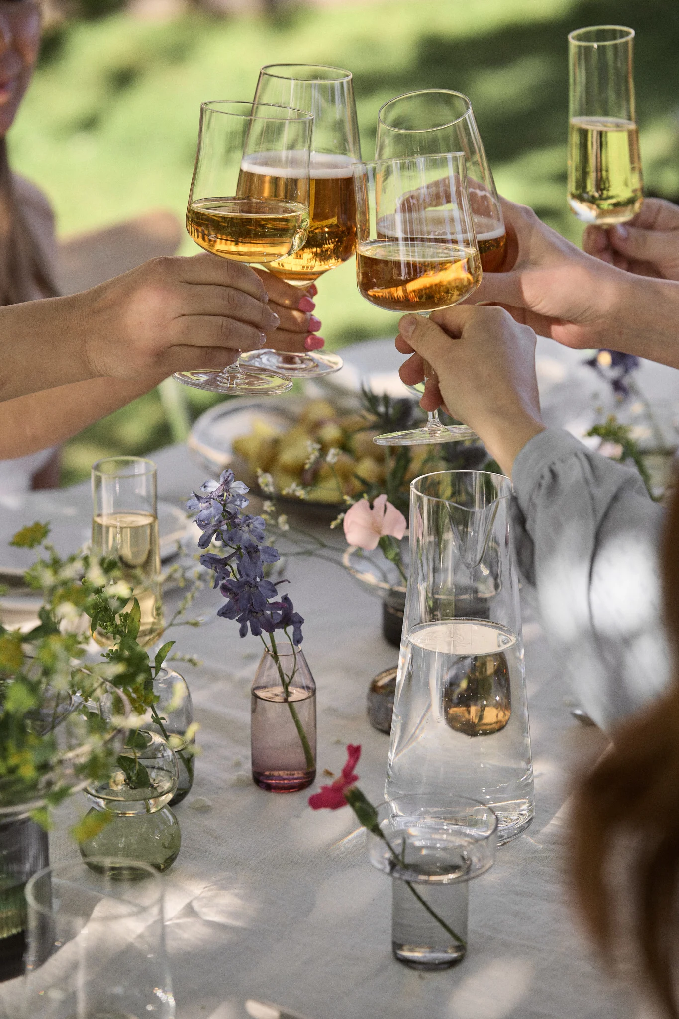 Disfruta del Midsummer con estas ideas suecas para fiestas de verano y brinda por la ocasión. Aquí puedes ver varias manos alzadas con los vasos de Essence de Iittala.