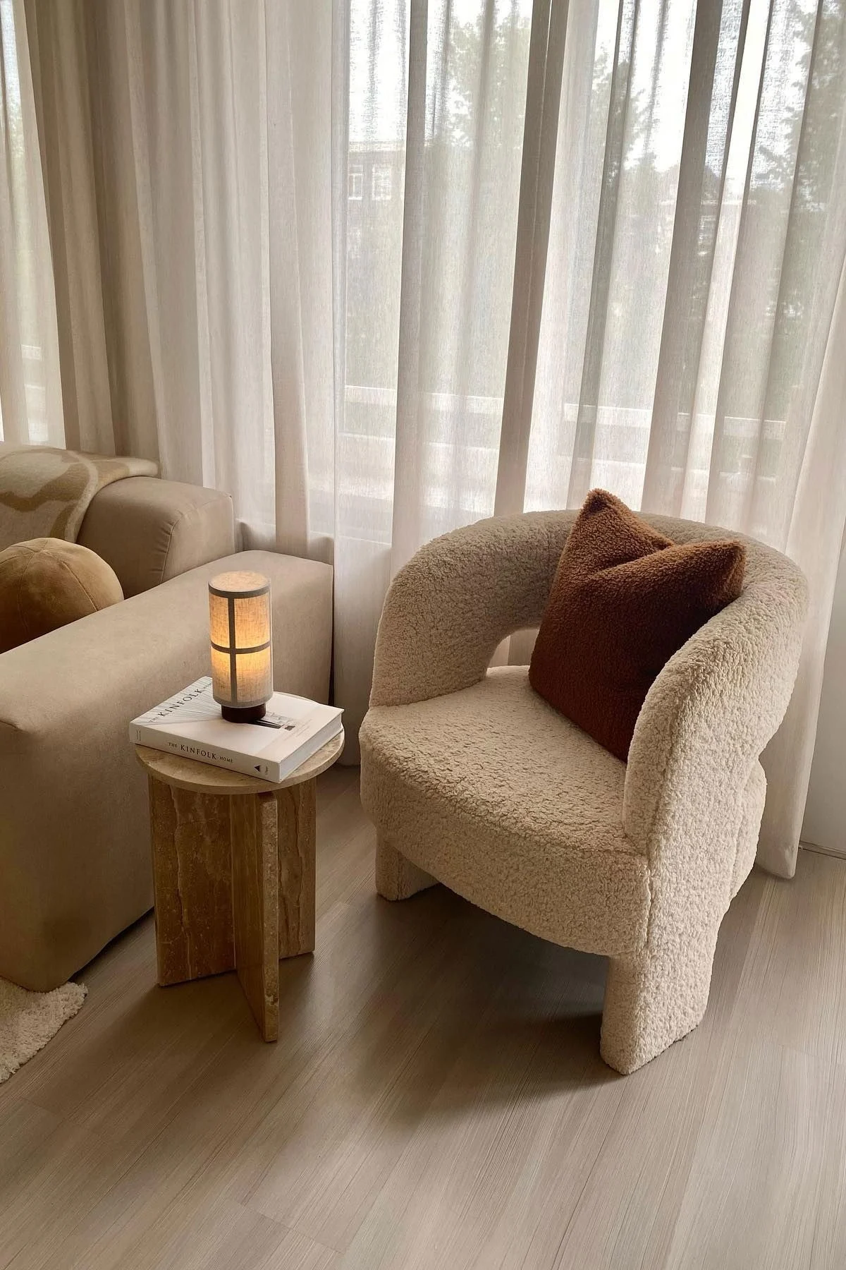 En una mesa de centro de mármol hay un libro, sobre él está la lámpara de mesa Hashira de Audo Copenhagen, a la izquierda un sofá y a la derecha un sillón.