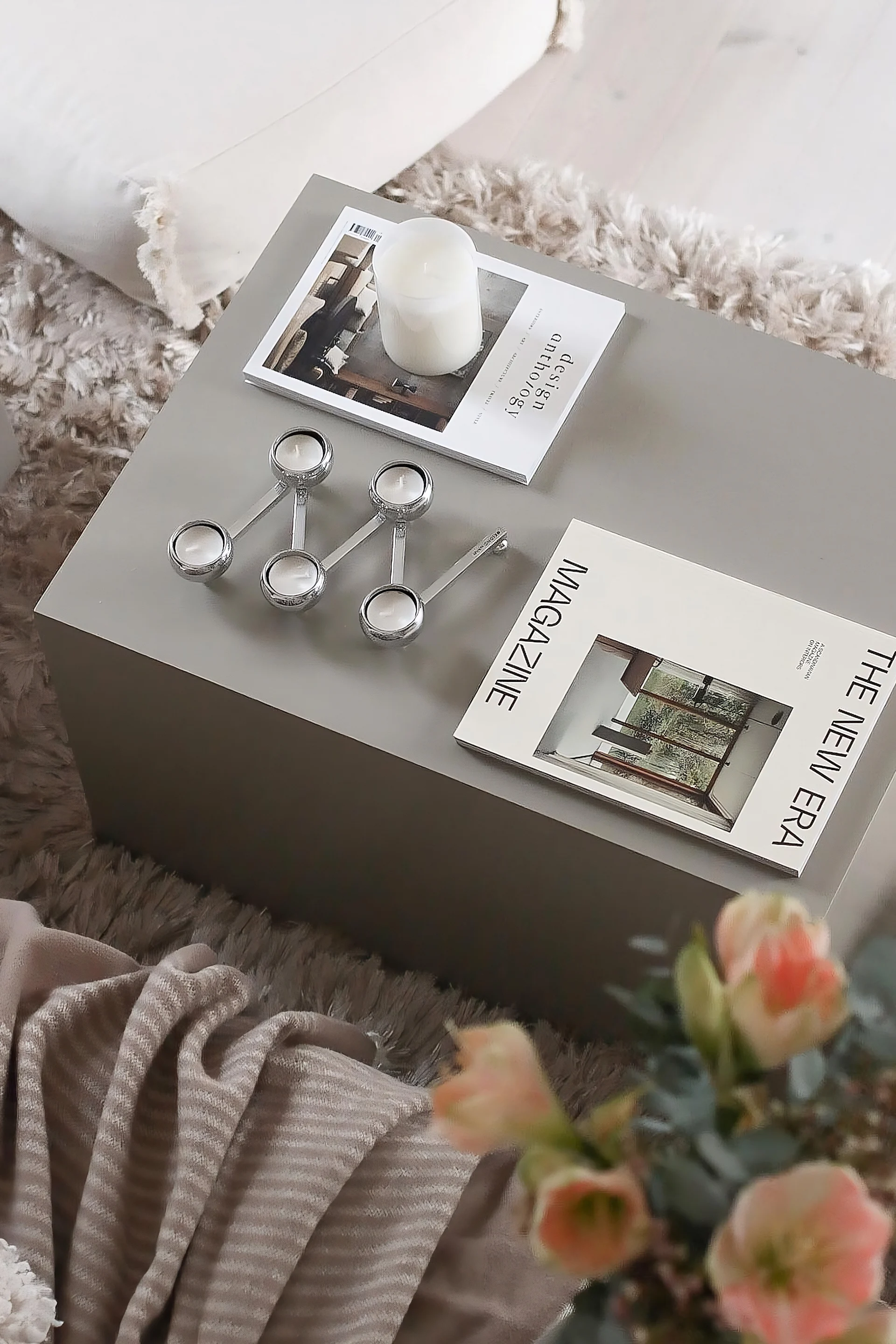 Una mesa de centro rectangular, decorada con revistas y el candelabro Constella de Klong.