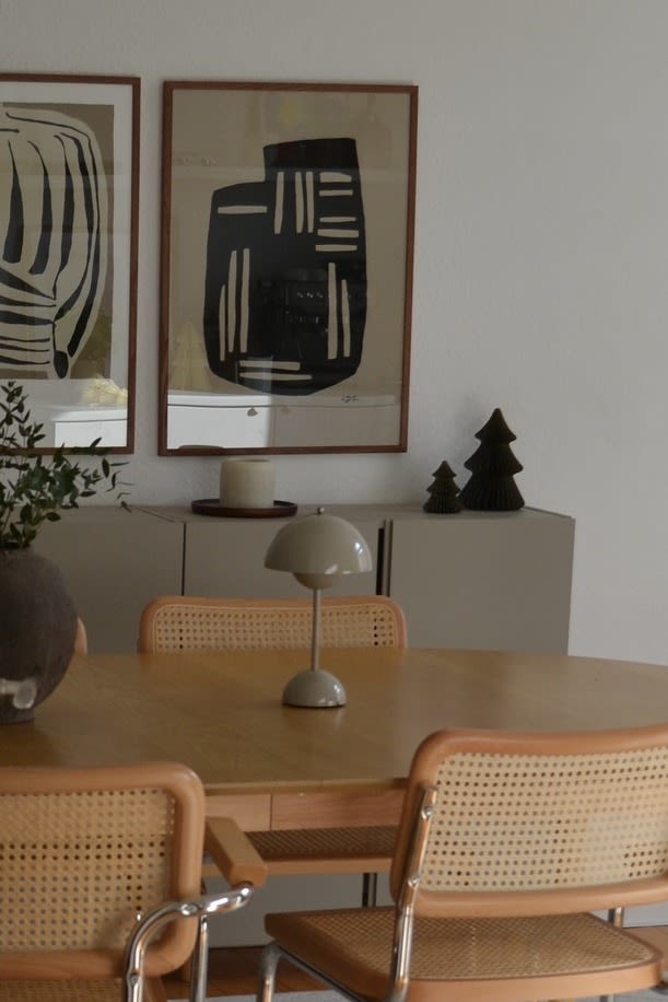 El grisáceo regresa a las tendencias de color para 2025. Aquí puedes ver la lámpara sin cable Flowerpot VP9 de &Tradition sobre una mesa de comedor de madera.