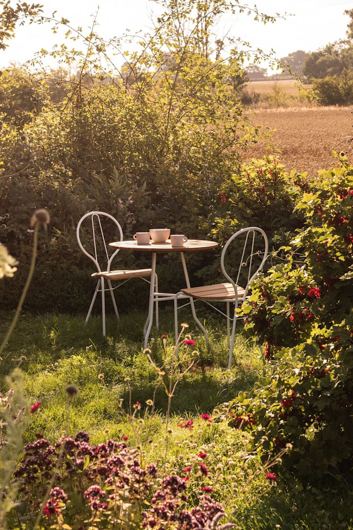 Tendencias en muebles de jardín 2025: un precioso jardín verde, con la mesa y dos sillas de la colección Pia de Gärsnäs en el centro.