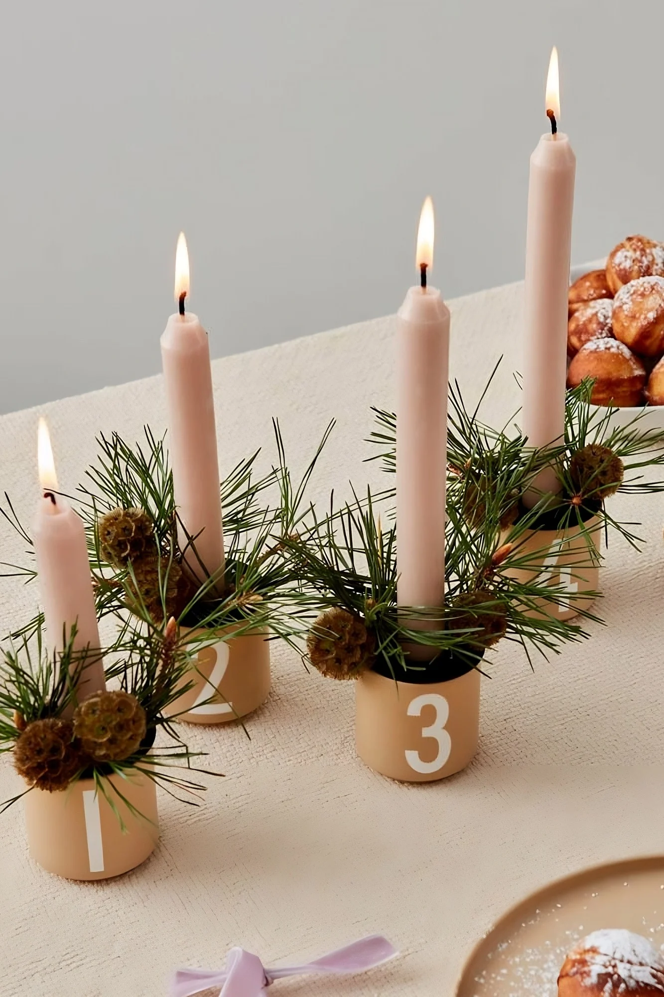 Sobre una mesa se encuentran las cuatro tazas de espresso de Design Letters, decoradas y usadas como portavelas navideños.