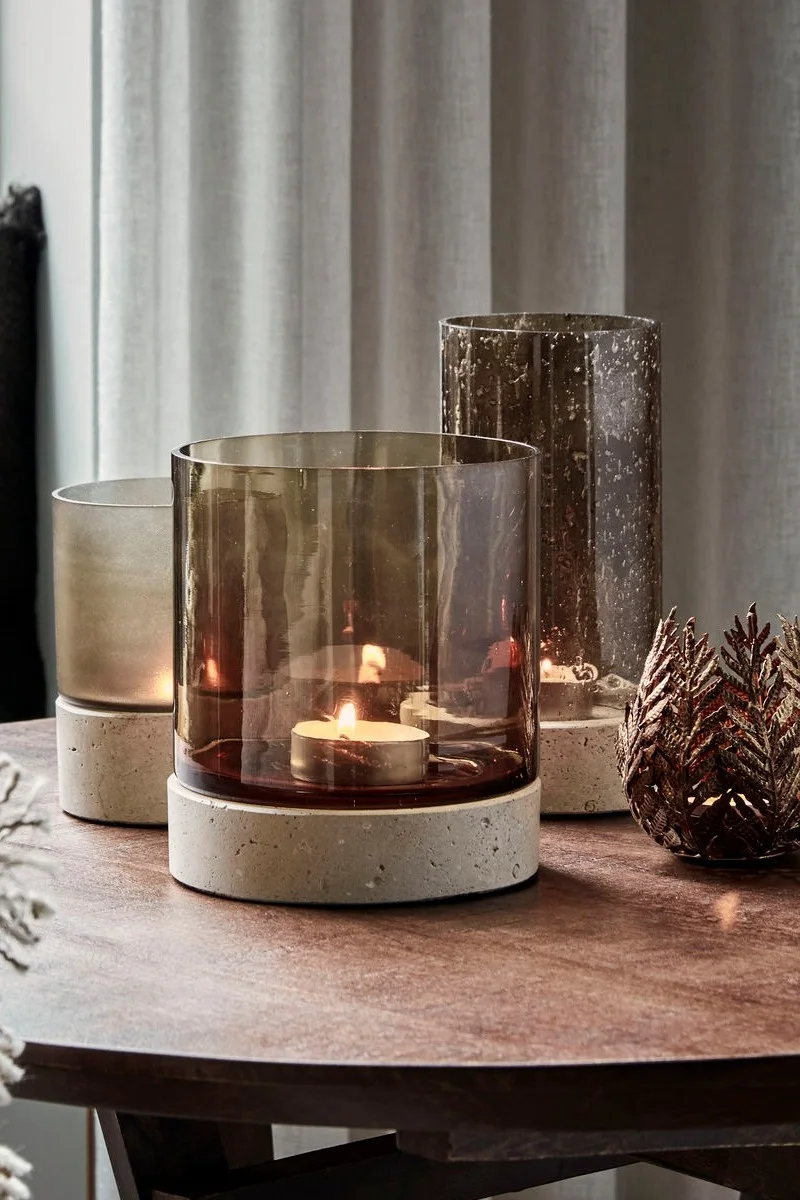 Una mesa de centro está decorada con motivos otoñales con tres candelabros Rivo de House Doctor de diferentes tamaños.