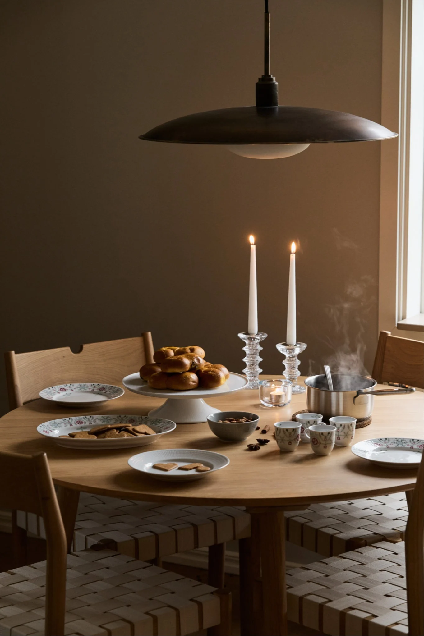 Una mesa decorada para Navidad con vajilla de la colección Swedish Grace Winter de Rörstrand, velas y dulces navideños.