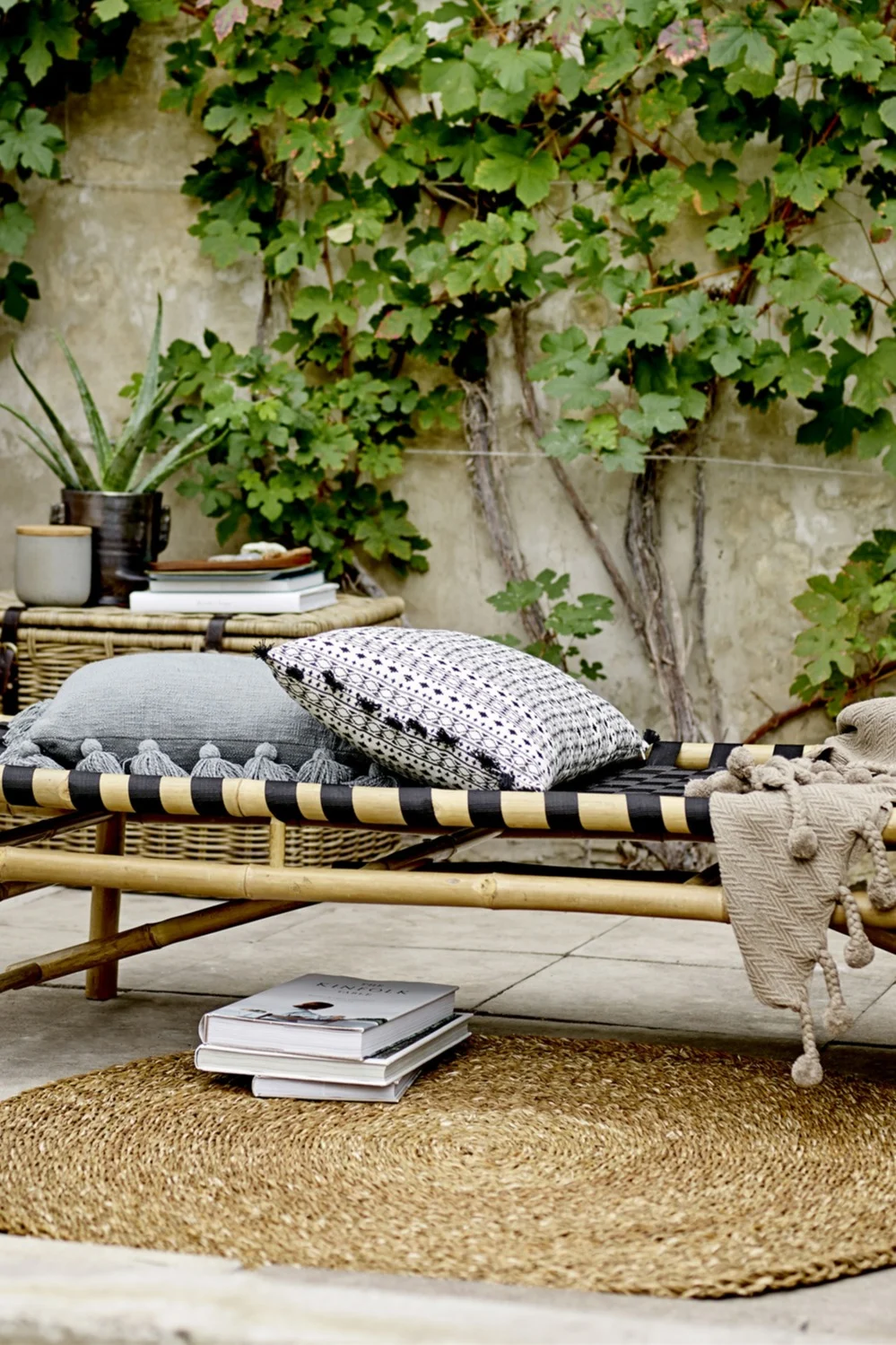 Decora con textiles para crear un balcón de estilo boho. Aquí puedes ver una tumbona en un balcón, debajo de la cual se encuentra la alfombra Eternal Jute de Ferm Living.