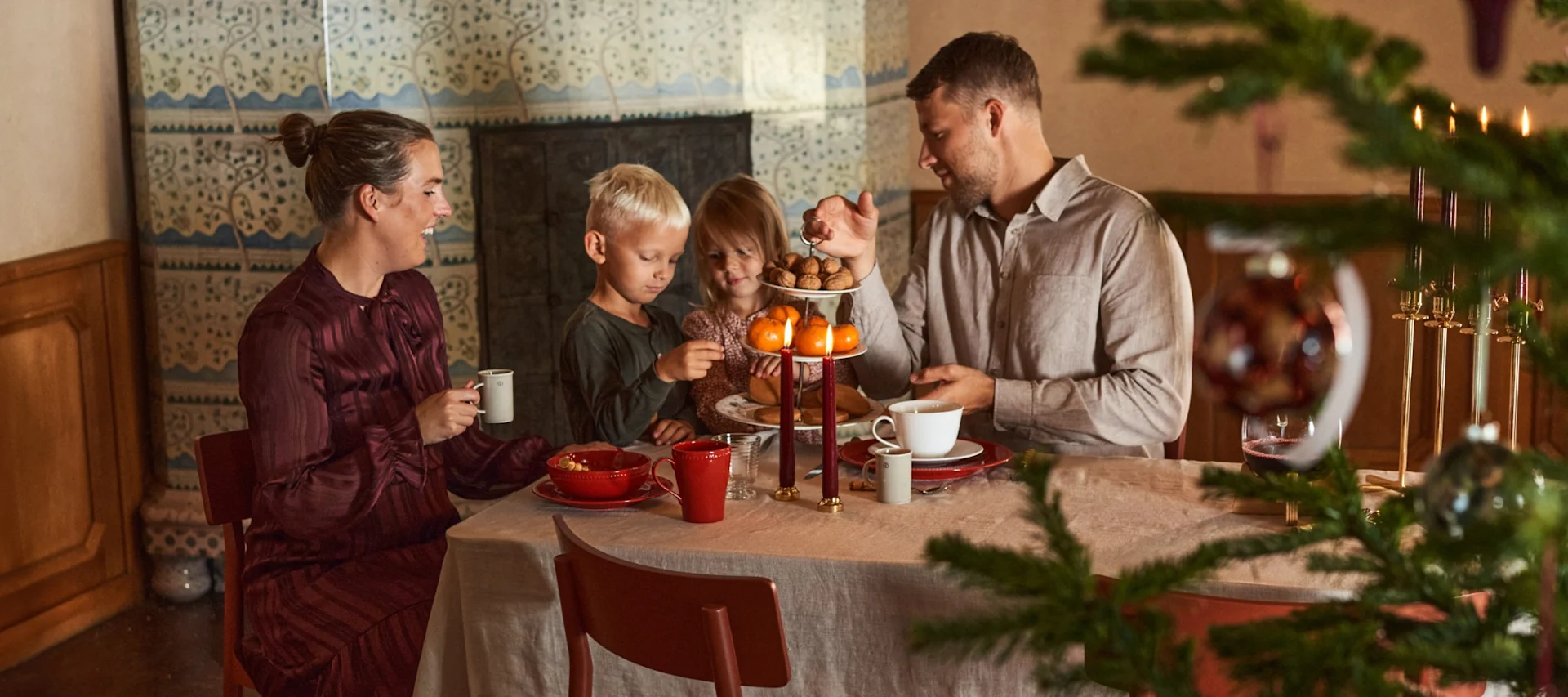 Una familia con dos niños está sentada a una mesa decorada de forma navideña.