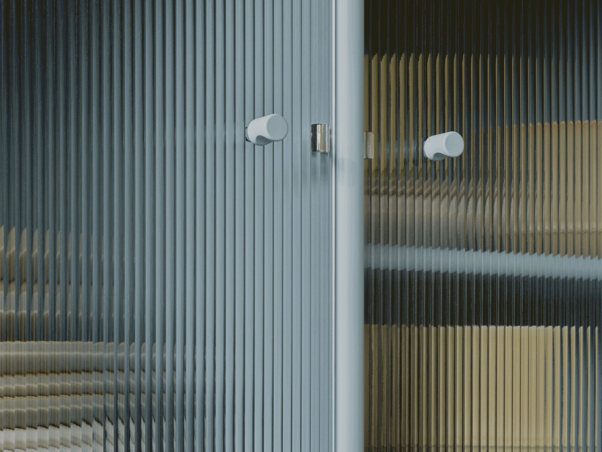 Primer plano de puerta de cristal estriado con dos tiradores redondos claros, mostrando colores distorsionados por la textura.