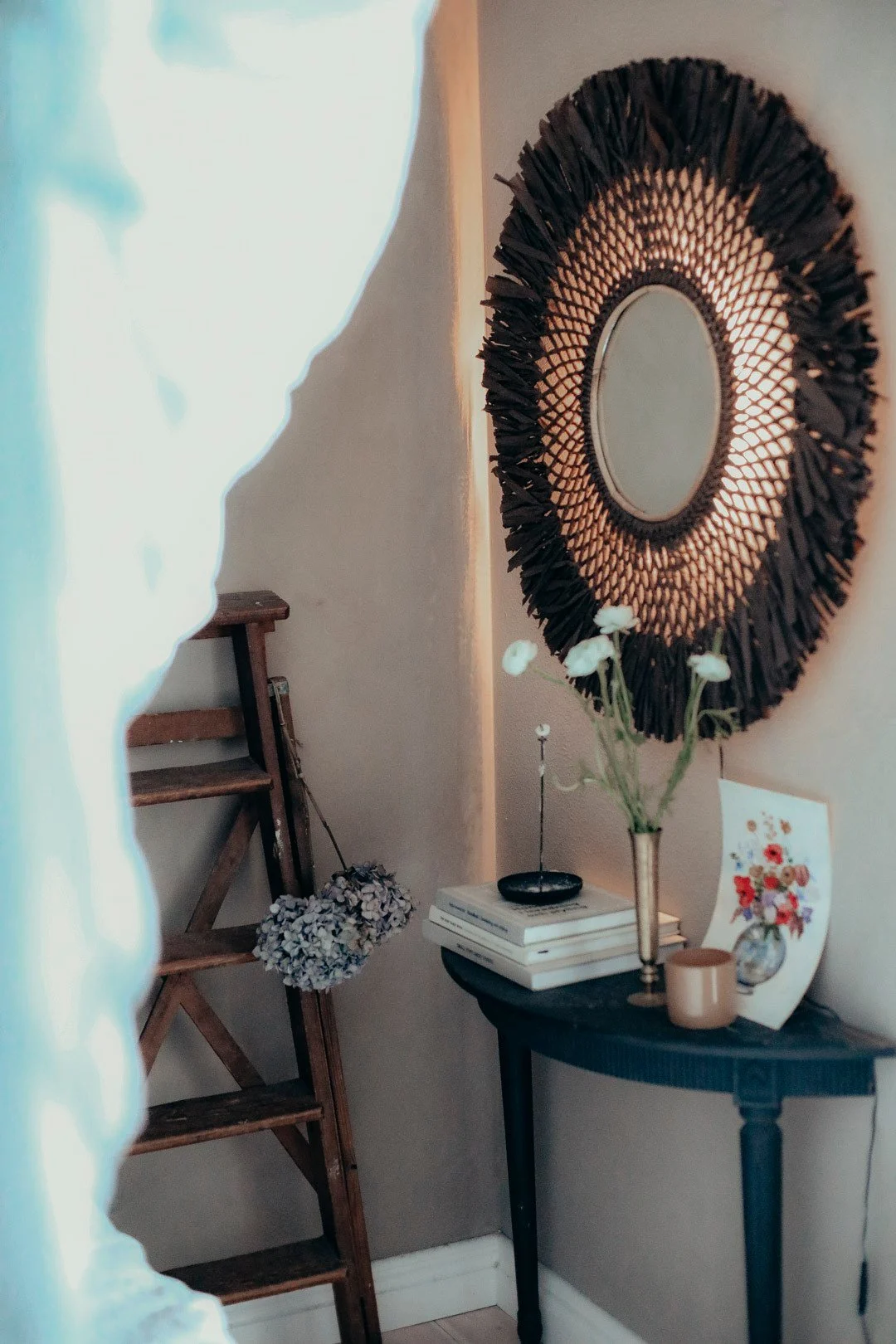 La decoración boho perfecta: el aplique boho con espejo de Globen Lighting cuelga en una habitación decorada en estilo boho.