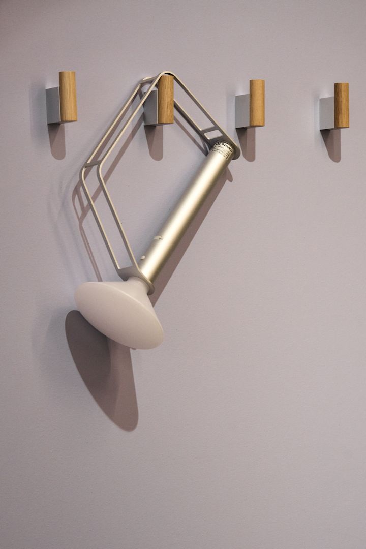 La lámpara de mesa Piton, plateada y portátil, de Muuto, cuelga de uno de los cuatro ganchos de la pared.