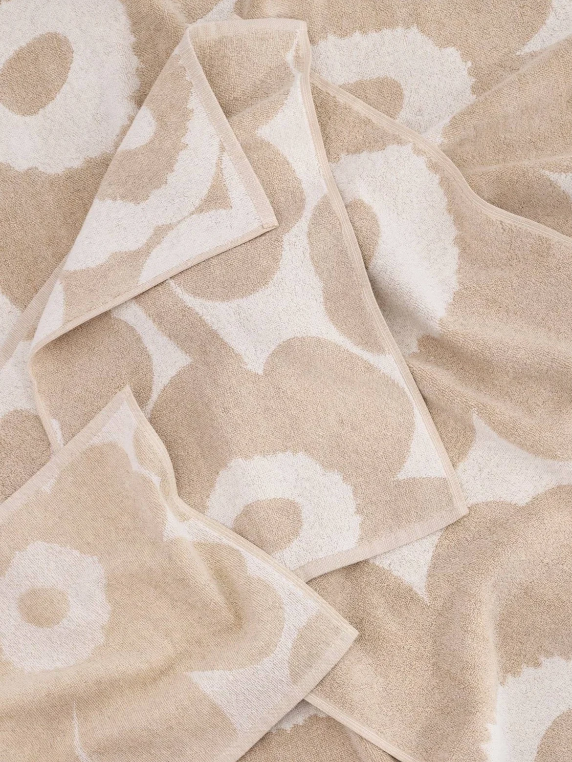 Varias toallas dobladas beige y blanquecinas con un gran estampado floral.