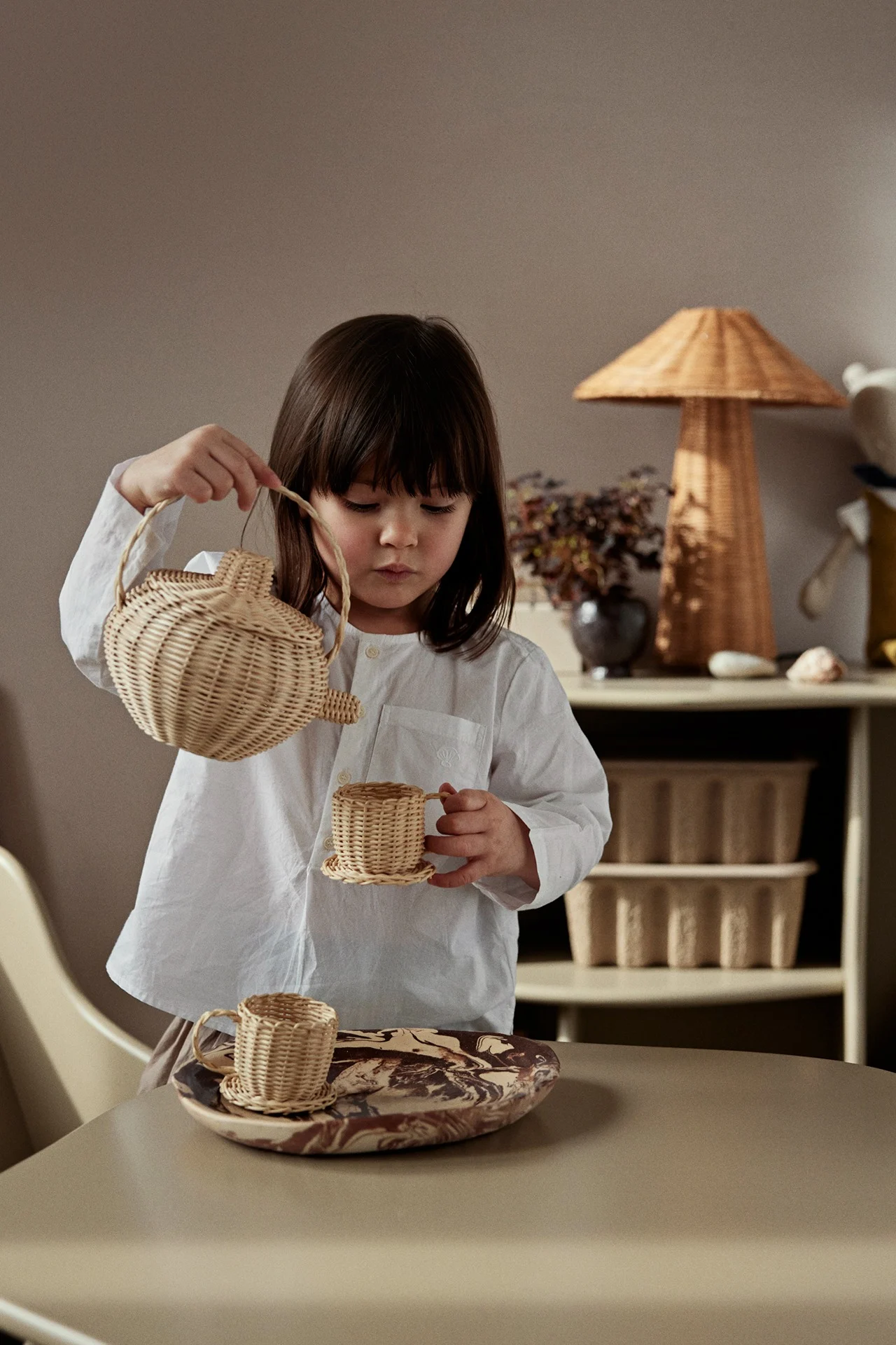 Las decoraciones que invitan al juego, como los juegos de té de ratán de Ferm Living, son lo último en decoración de habitaciones infantiles. Se puede jugar con este juego y, cuando no se utiliza, es realmente bonito como detalle interior.