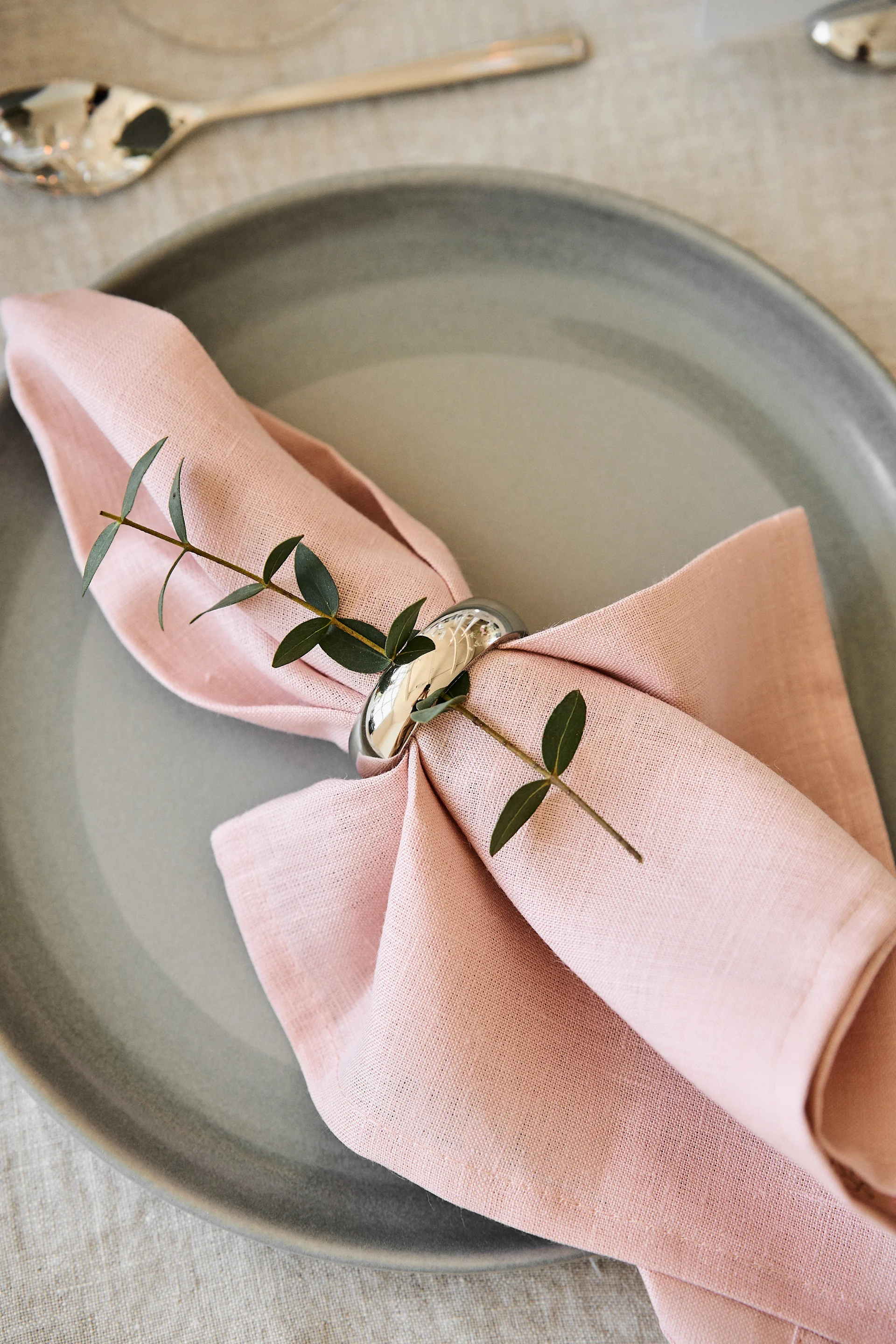 Decora la mesa de tu cena romántica en casa con colores agradables. Aquí puedes ver la servilleta Clean en Dusty Rose de Scandi Living sobre un plato con servilletero.