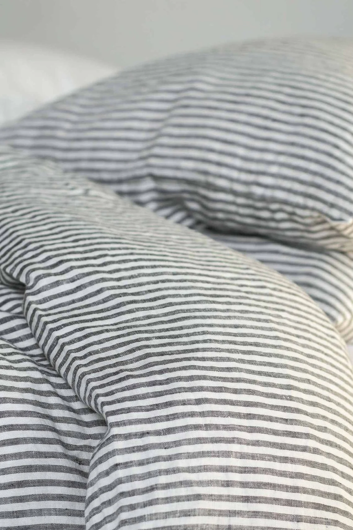 Primer plano de una cama con ropa de cama de lino a rayas blancas y negras.