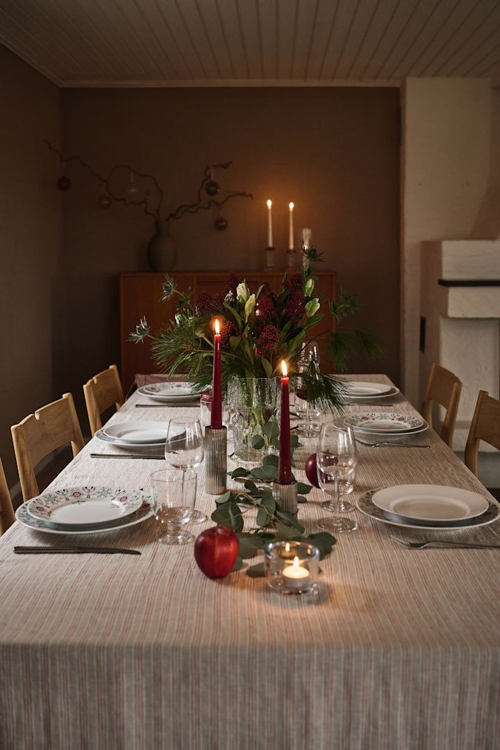 Una idea atmosférica y sencilla para poner la mesa en Navidad con velas rojas y vajilla navideña estampada.