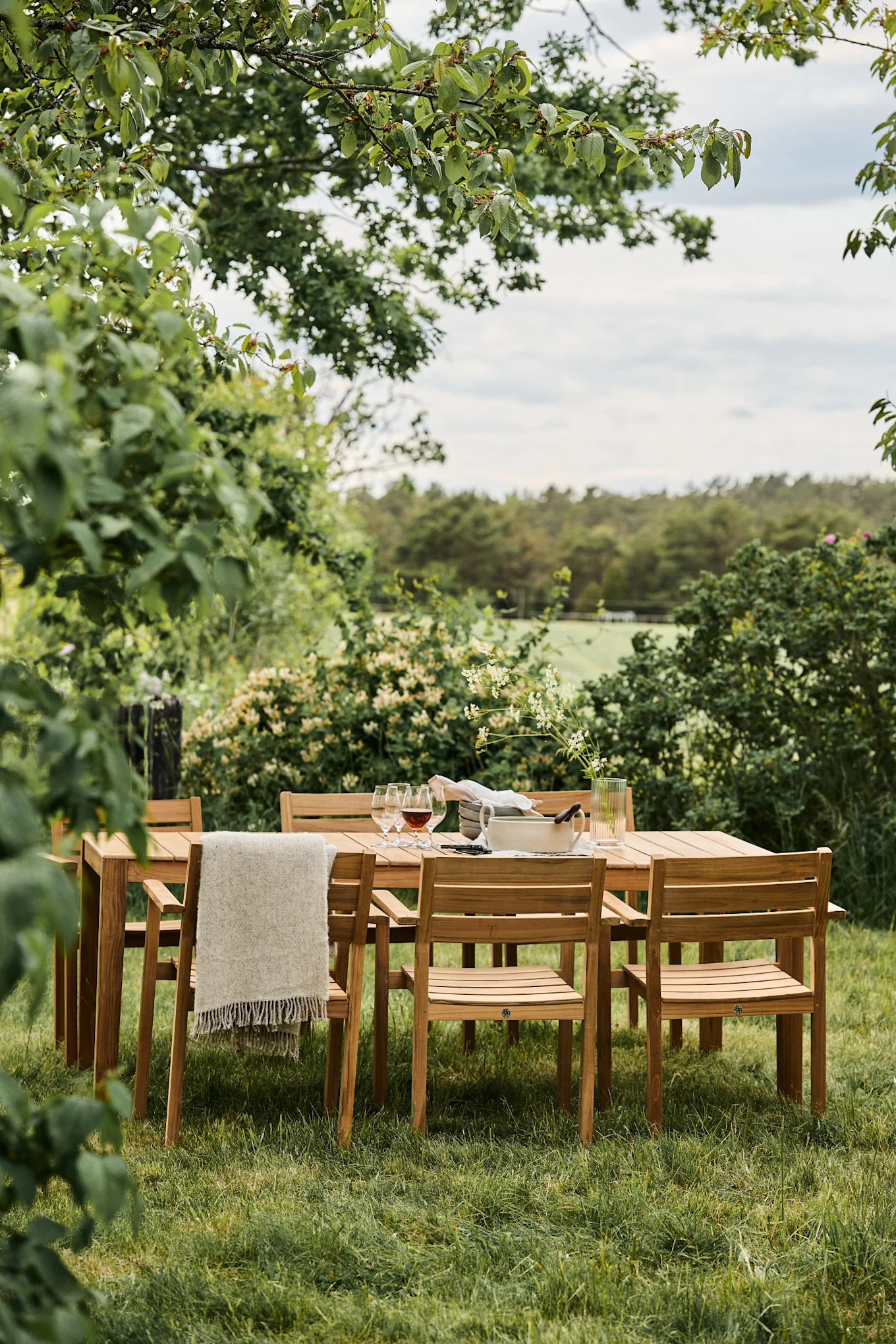 Tendencias en muebles de jardín 2025: las sillas Sköndal de 1898 se sitúan alrededor de una mesa en un jardín muy florido.