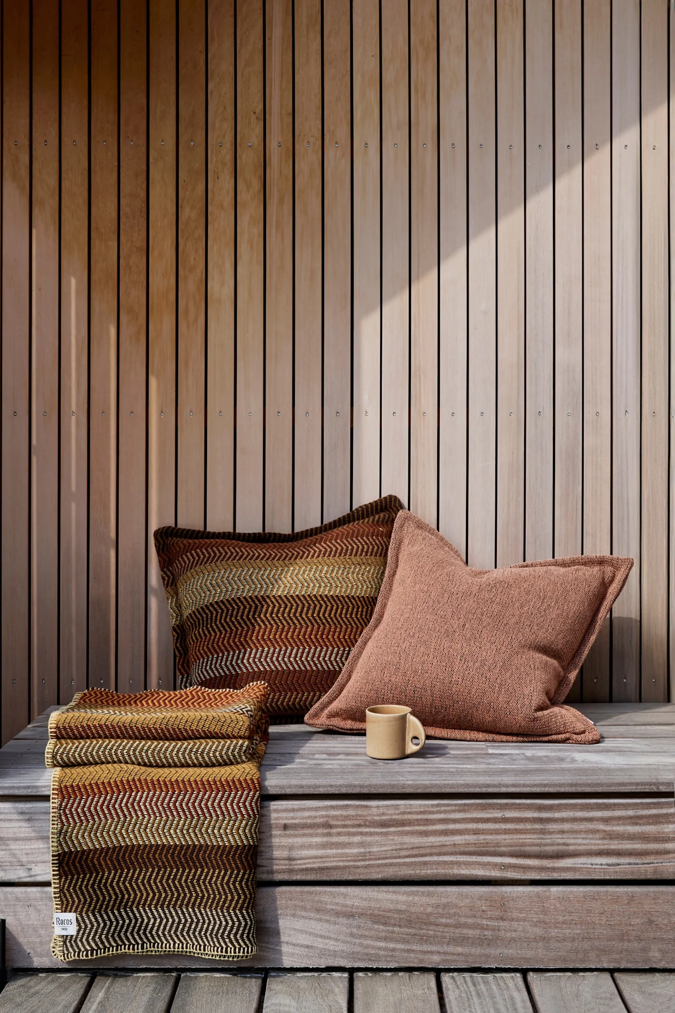 Decorar un balcón boho: para el estilo boho, es fundamental elegir los colores adecuados. Aquí puede ver el cojín Fri de Røros Tweed en tonos marrones, rojos y amarillos en un balcón.