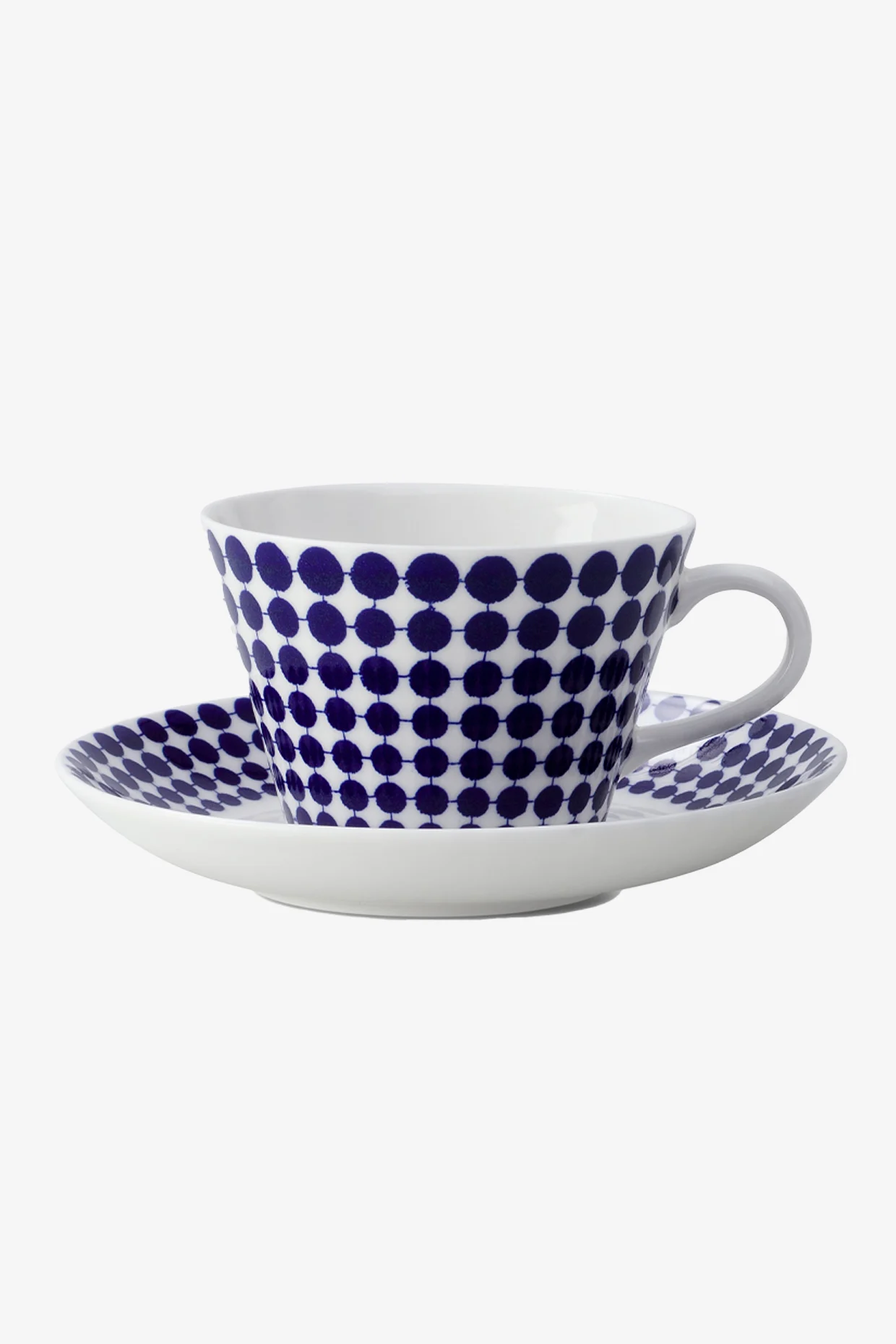 Taza y platillo blancos con un patrón de lunares azules.