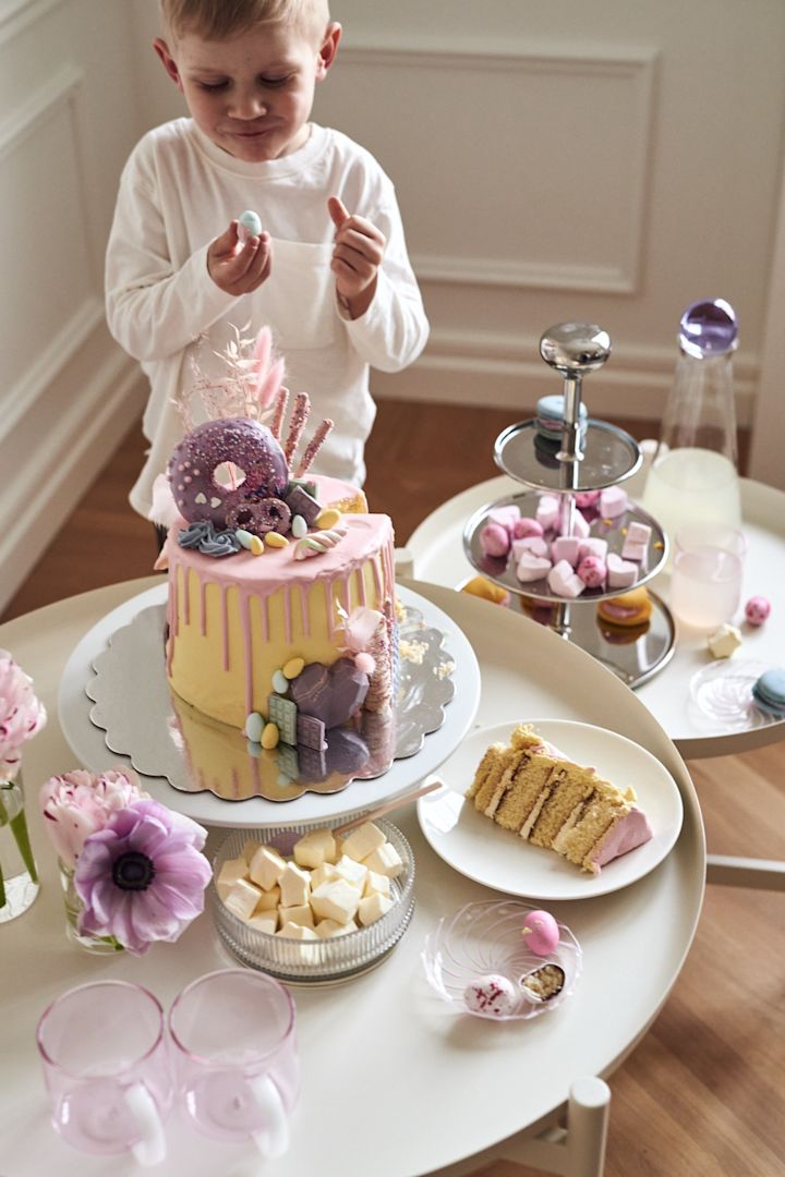 Una mesa de postres de Pascua es una idea genial para una decoración colorida y divertida. Aquí ves a un niño disfrutando de un trozo de tarta.