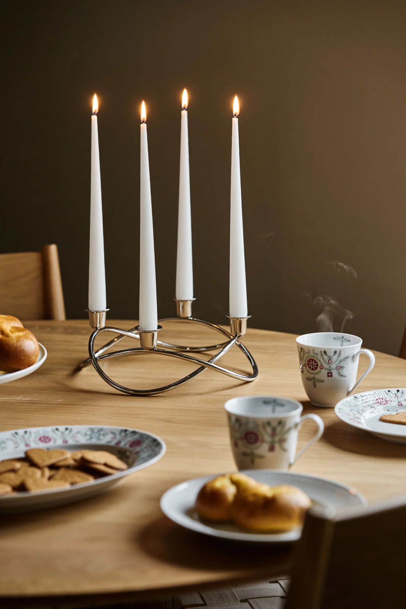 La decoración adecuada también es parte de un Glöggmingel: aquí puede ver el candelabro Season de Georg Jensen sobre una mesa, junto a vajilla navideña con galletas de jengibre y bollos de azafrán.