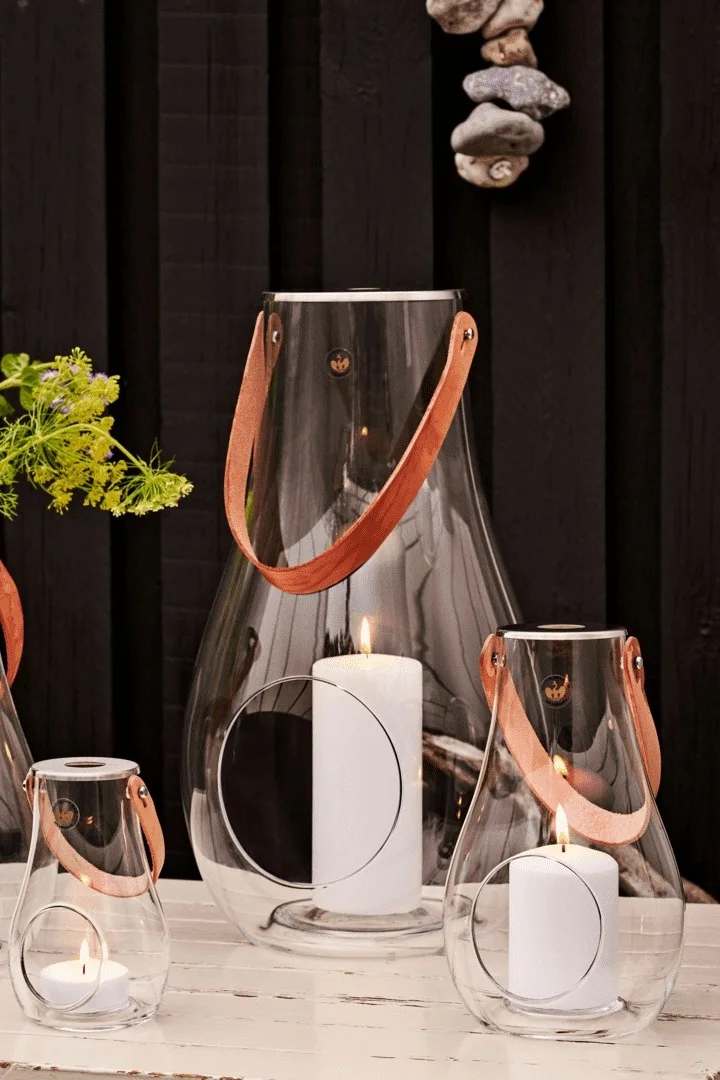 Lo mejor es colocar los farolillos y portavelas al aire libre en grupos. Aquí puedes ver el farol Design with Lights de Holmegaard en varios tamaños.