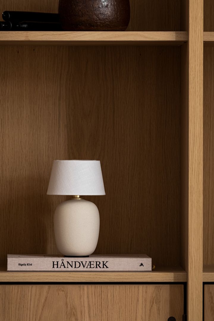 La lámpara tipo seta más de moda de esta temporada: la lámpara de mesa portátil Torso de Menu, vista aquí en una estantería de madera.