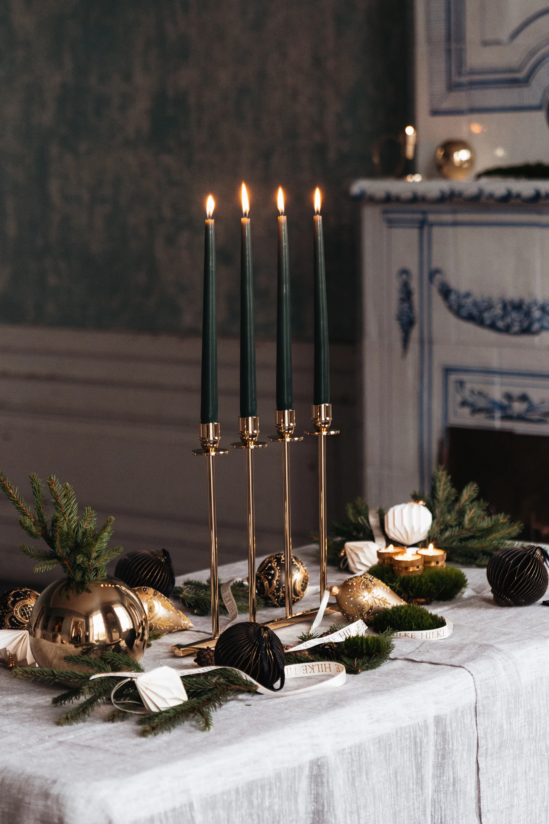 Sobre una mesa decorada para Navidad se encuentra el portavelas Alto de Hilke, con velas verdes.