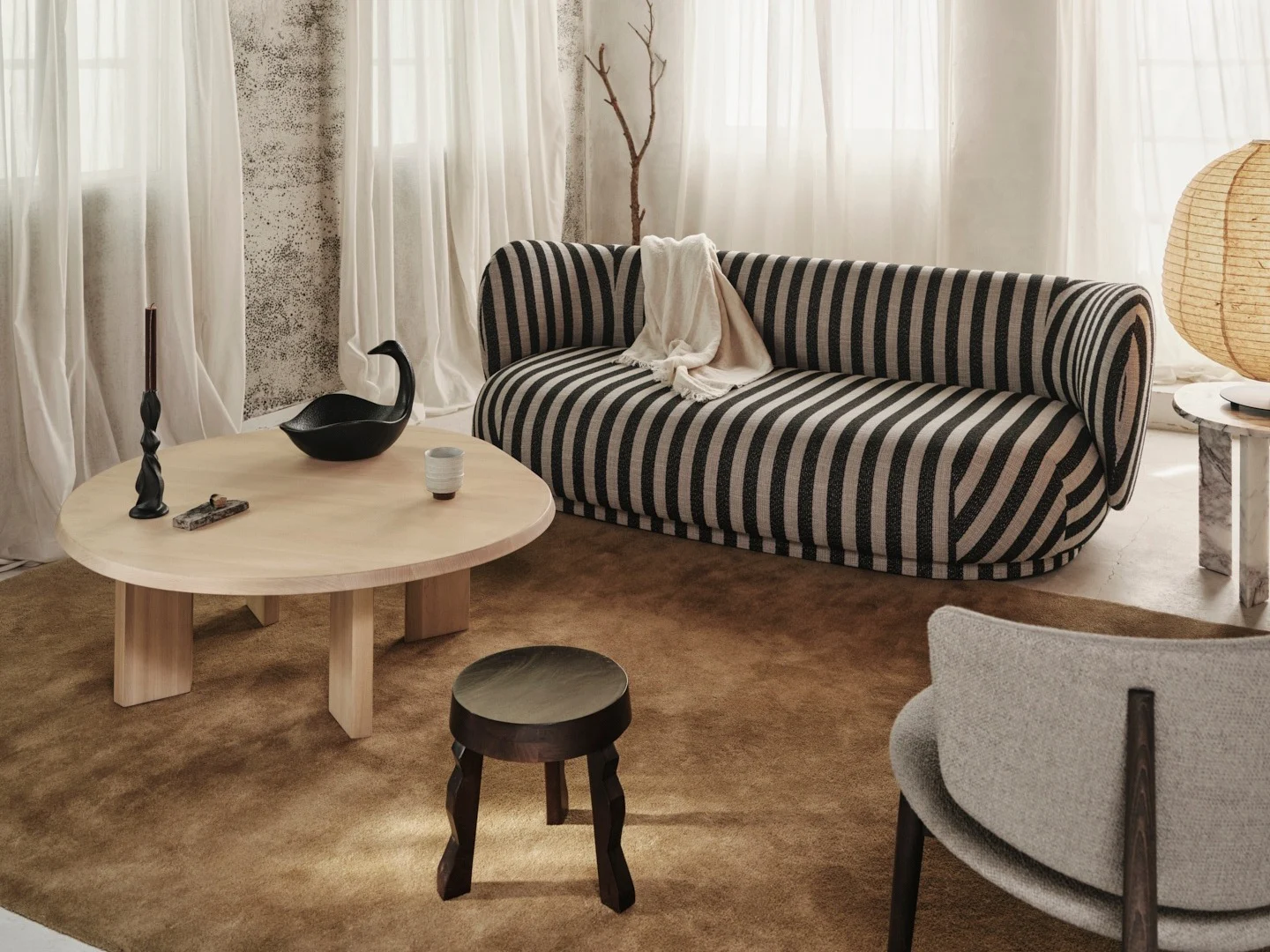Acogedora sala de estar con sofá a rayas blanco y negro, mesa de centro de madera clara y techo de vigas de madera rústicas.