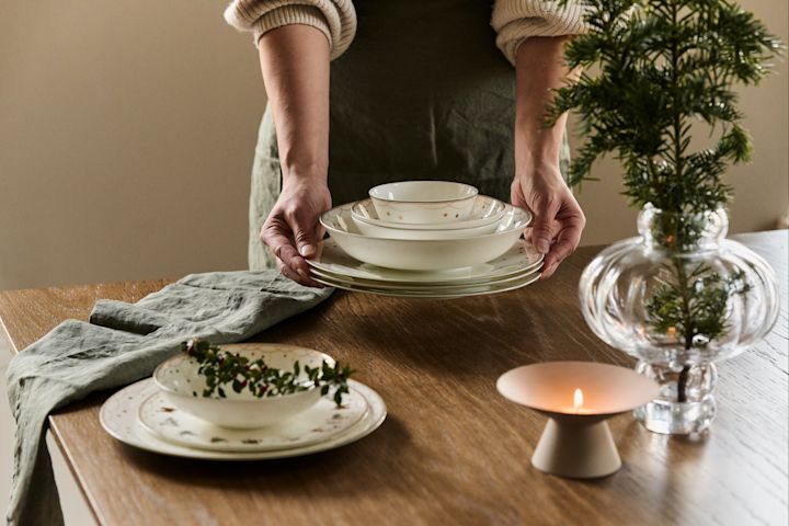 Decora la mesa puesta con ramas de abeto, por ejemplo, en un jarrón, sobre el plato o en la servilleta, para crear un ambiente navideño en el hogar.