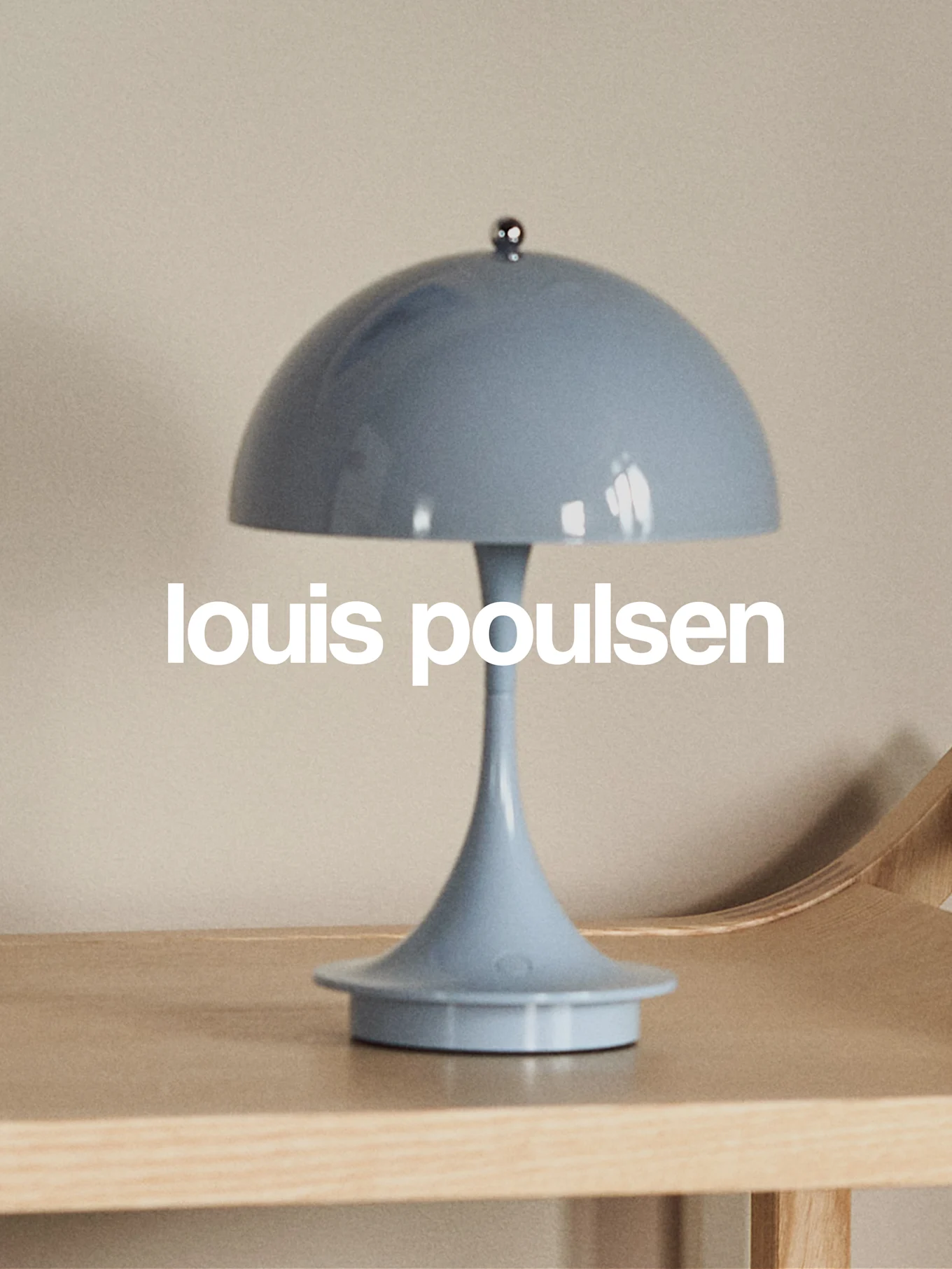 Lámpara de mesa azul claro con forma de hongo sobre una superficie de madera con el texto 'louis poulsen'.