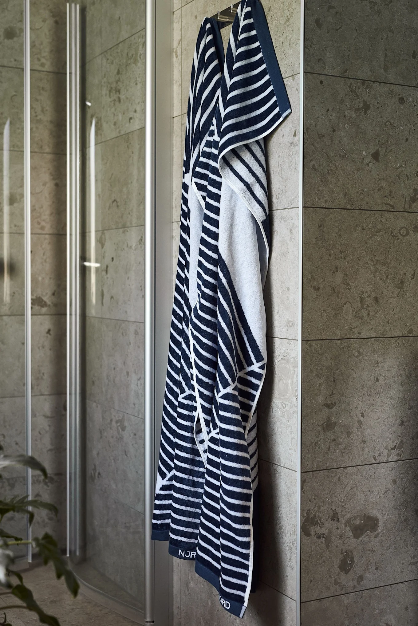 Regala la toalla de baño Stripes de NJRD como regalo del Día del Padre para los amantes de la sauna, en la imagen colgada delante de una ducha.