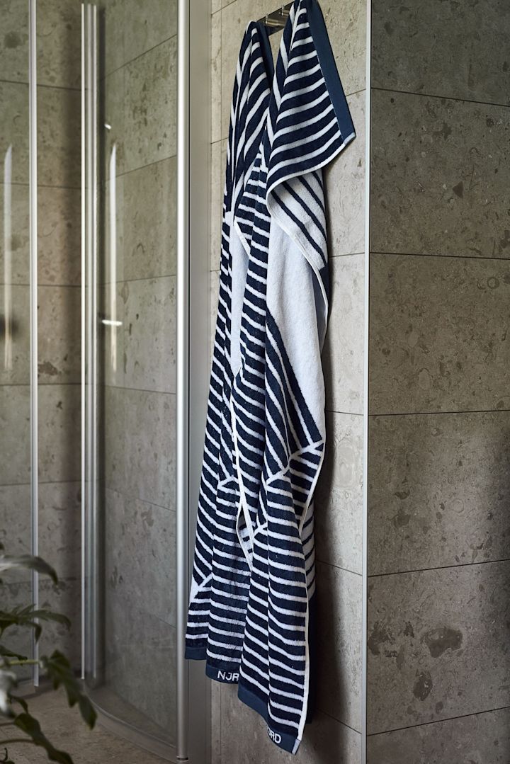 Regala la toalla de baño Stripes de NJRD como regalo del Día del Padre para los amantes de la sauna, en la imagen colgada delante de una ducha.