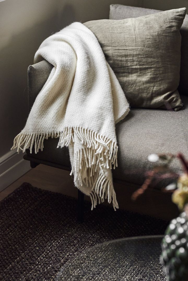Una acogedora manta es un excelente regalo para el Día de la Madre. Aquí puedes ver la manta blanca Sandstone de Scandi Living sobre un sofá.
