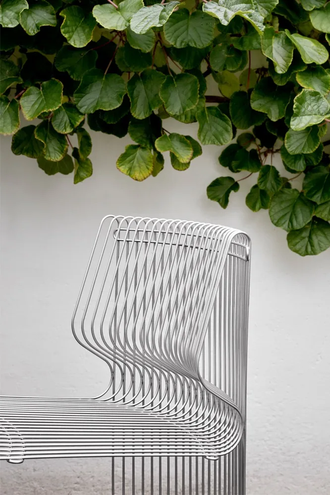 Enmarcado por plantas trepadoras, se encuentra un módulo del sofá Pantonova al aire libre.