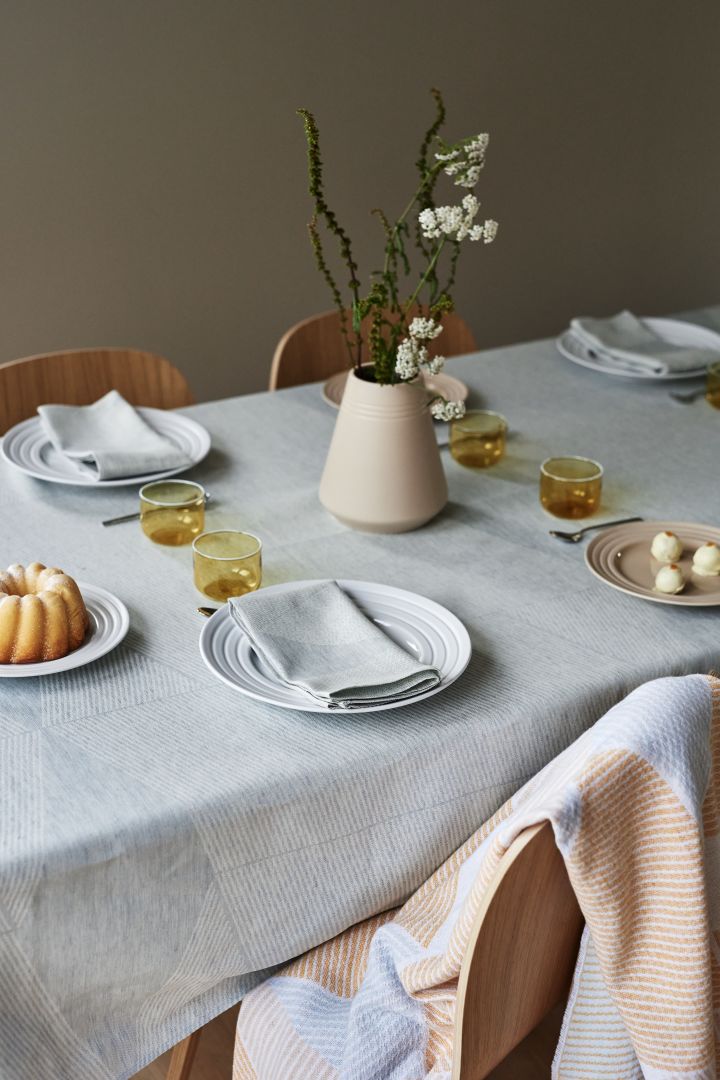 Una idea elegante para poner la mesa en tonos pastel suaves de NJRD con un mantel azul y una manta azul y amarilla.