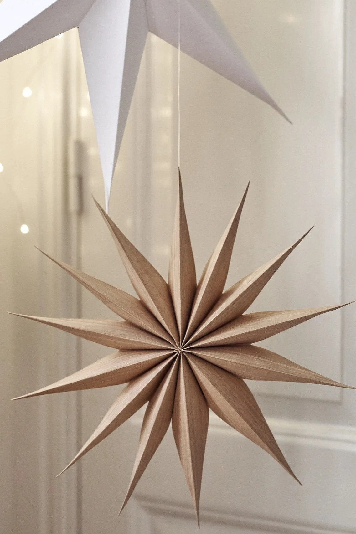 La estrella de Navidad Venok de Broste Copenhagen cuelga en un grupo de estrellas en el salón.