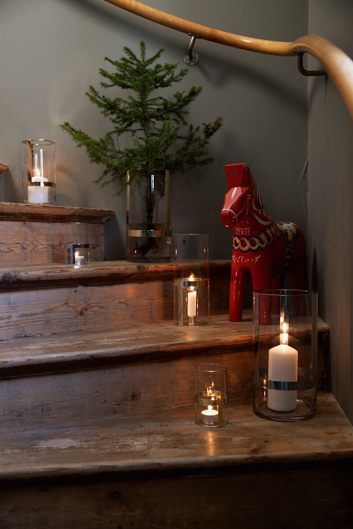 Decora también la escalera para entrar en el ambiente navideño. Coloca la jarrón Hold de Sagaform en diferentes tamaños en varios escalones y llénalos con velas y ramas de abeto. Un caballo Dala completa la decoración.