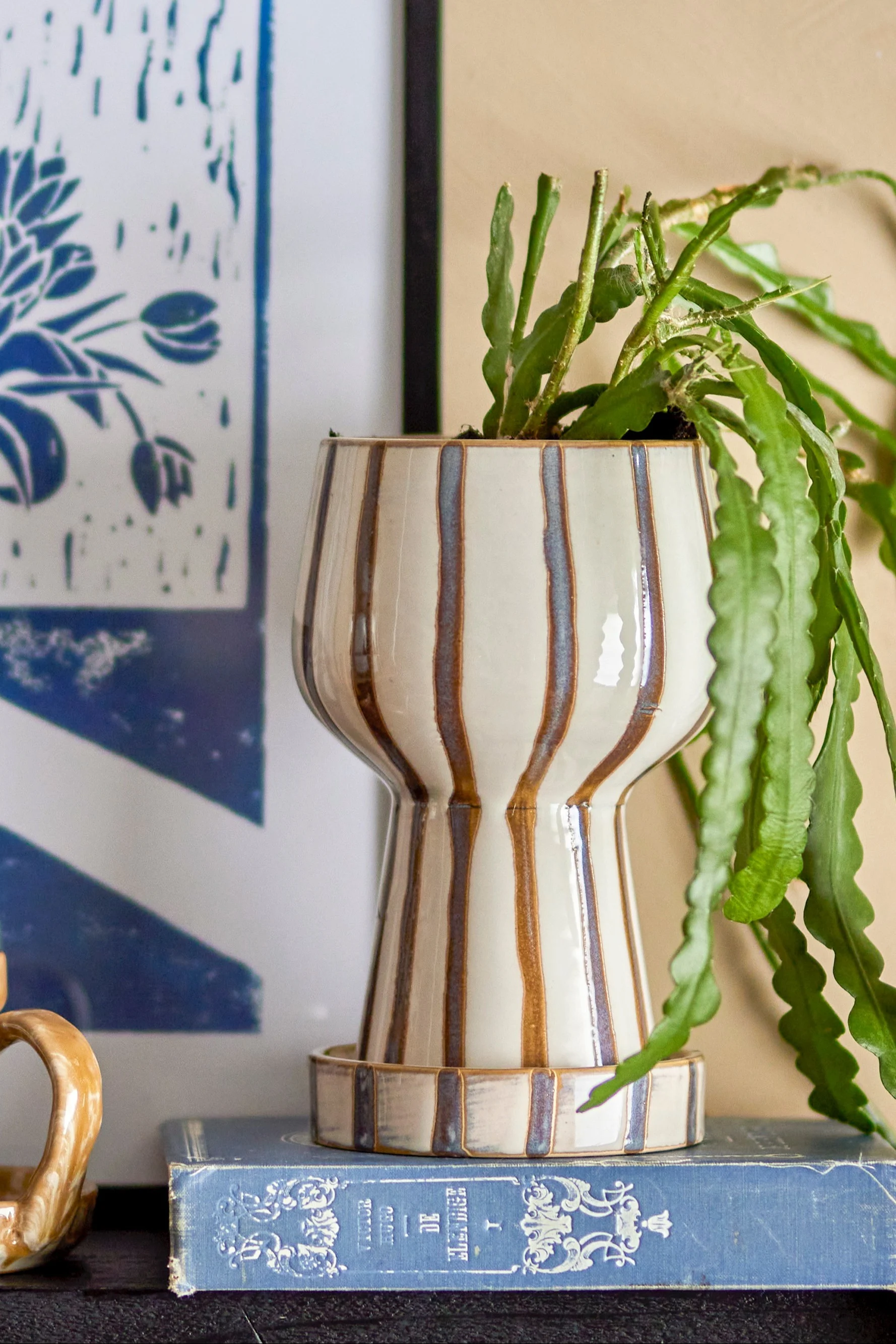 La decoración boho perfecta: la maceta Agna a rayas con forma de cáliz y una planta dentro.