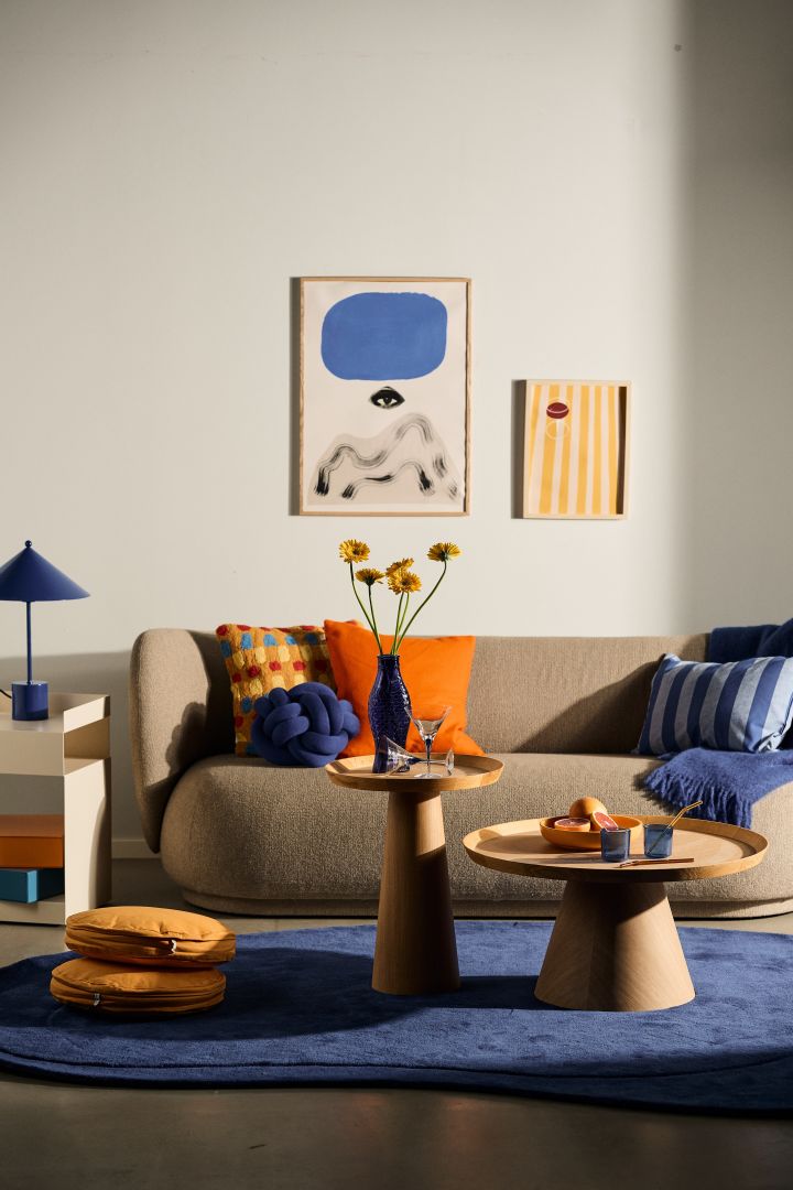 Decora según las tendencias de diseño escandinavo de interiores de 2024 y usa mucho color y patrones para combinar y mezclar. Aquí tienes una sala de estar con decoración en azul, naranja y amarillo.