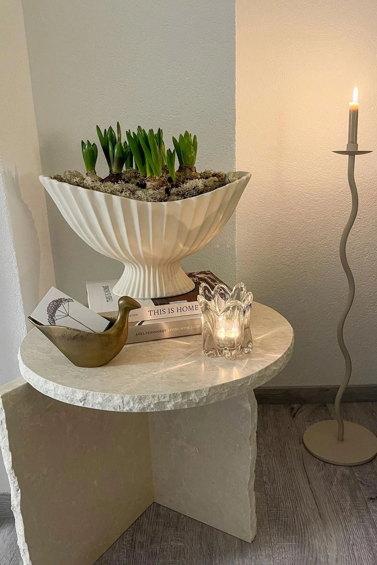 La mesa Mineral Sculptural está decorada con el cuenco Fountain, ambos de Ferm Living, y otros pequeños objetos. Al lado se encuentra el gran candelabro Curved de Cooee Design.