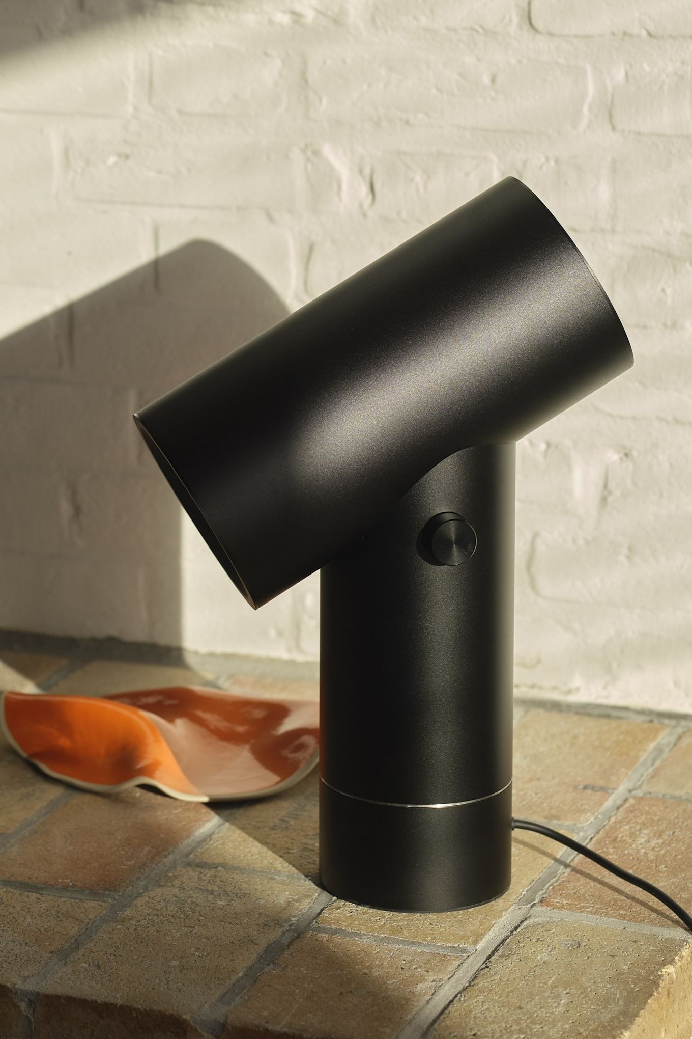 La lámpara de mesa Beam negra de Muuto en un entorno de azulejos.