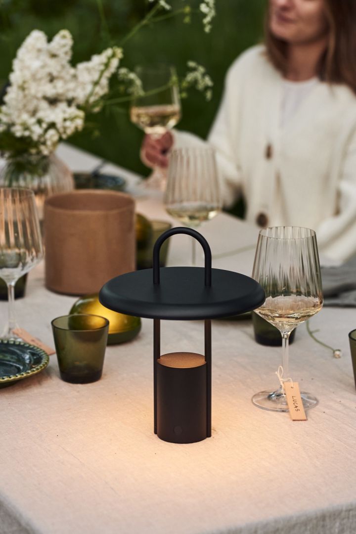 La lámpara portátil Pier LED de Stelton es una lámpara de mesa inalámbrica que luce perfecta en la mesa preparada para una cena al aire libre.