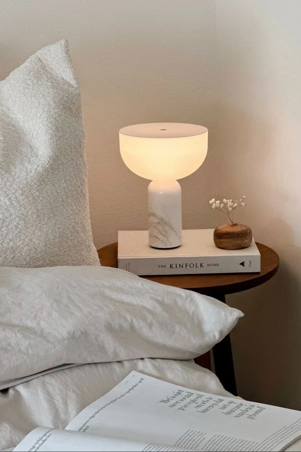 Junto a la cama de @wonen.met.lef hay un taburete con la lámpara de mesa Kizu de New Works.