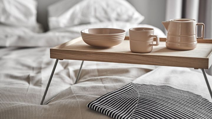 Lagom también significa empezar el día de forma relajada. Aquí, una taza, una jarra y un bol de la colección Lines de NJRD reposan sobre una bandeja de desayuno en la cama.