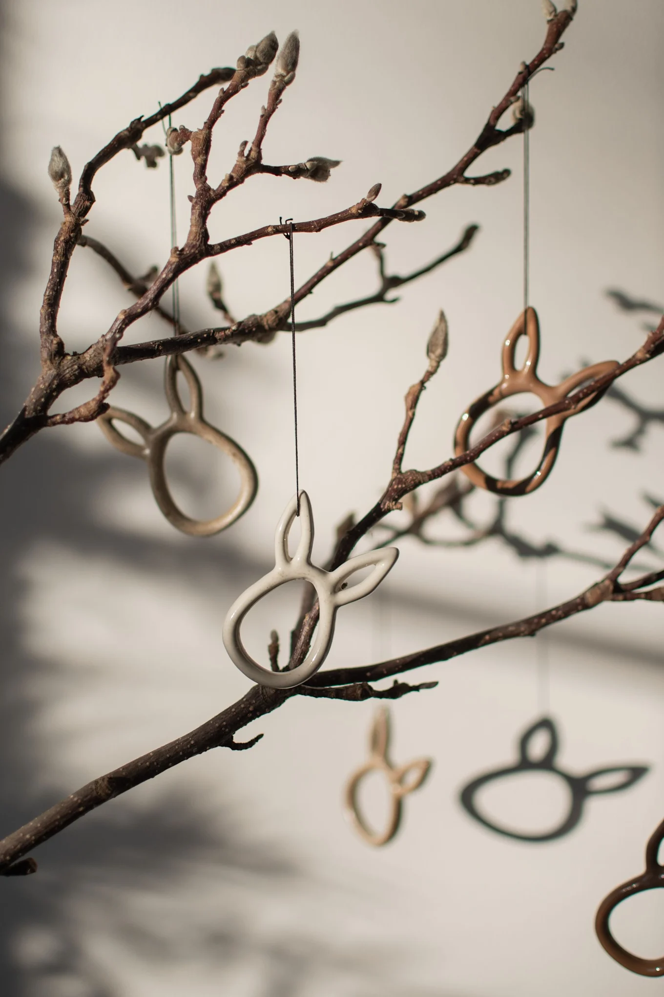 Los colgantes de Pascua en forma de conejo Sprinkle de DBKD cuelgan de unas ramas.