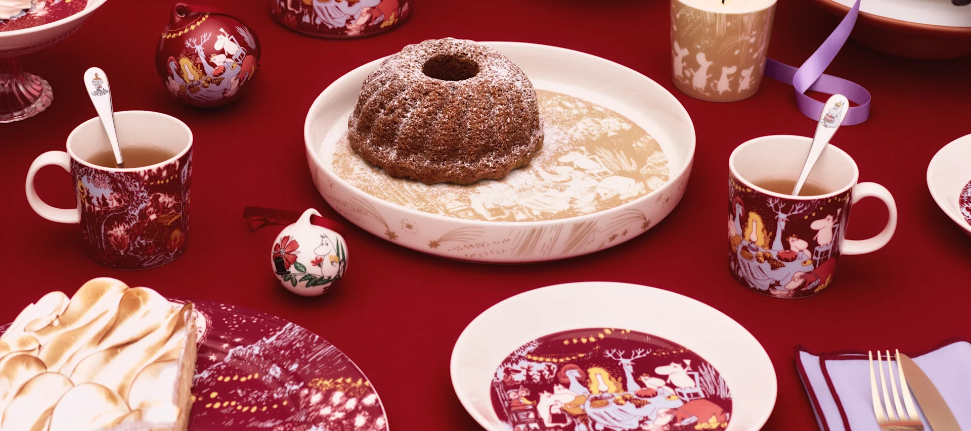 Varias tazas de Mumin Arabia están sobre una mesa en el exterior, junto a una jarra.