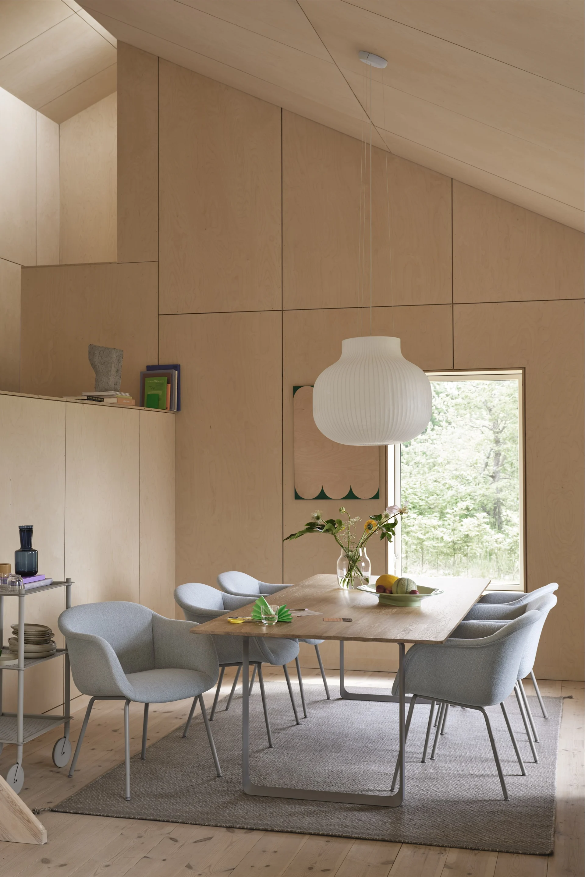 Alfombras para el comedor: la alfombra de lana Ply en gris de Muuto está colocada en un comedor de estilo escandinavo, decorado con sillas azul claro y detalles de madera.