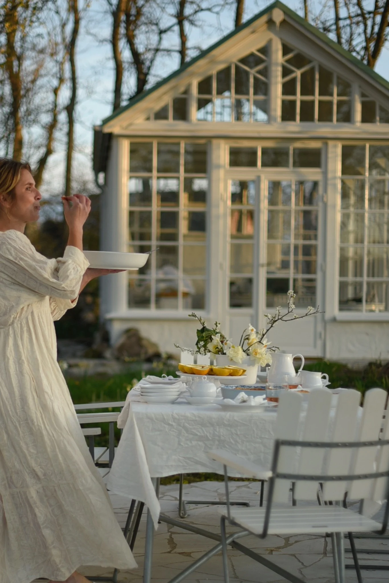 Una mesa con sillas A2 blancas de Grythyttan delante de un invernadero en el jardín de @khouri.julia.