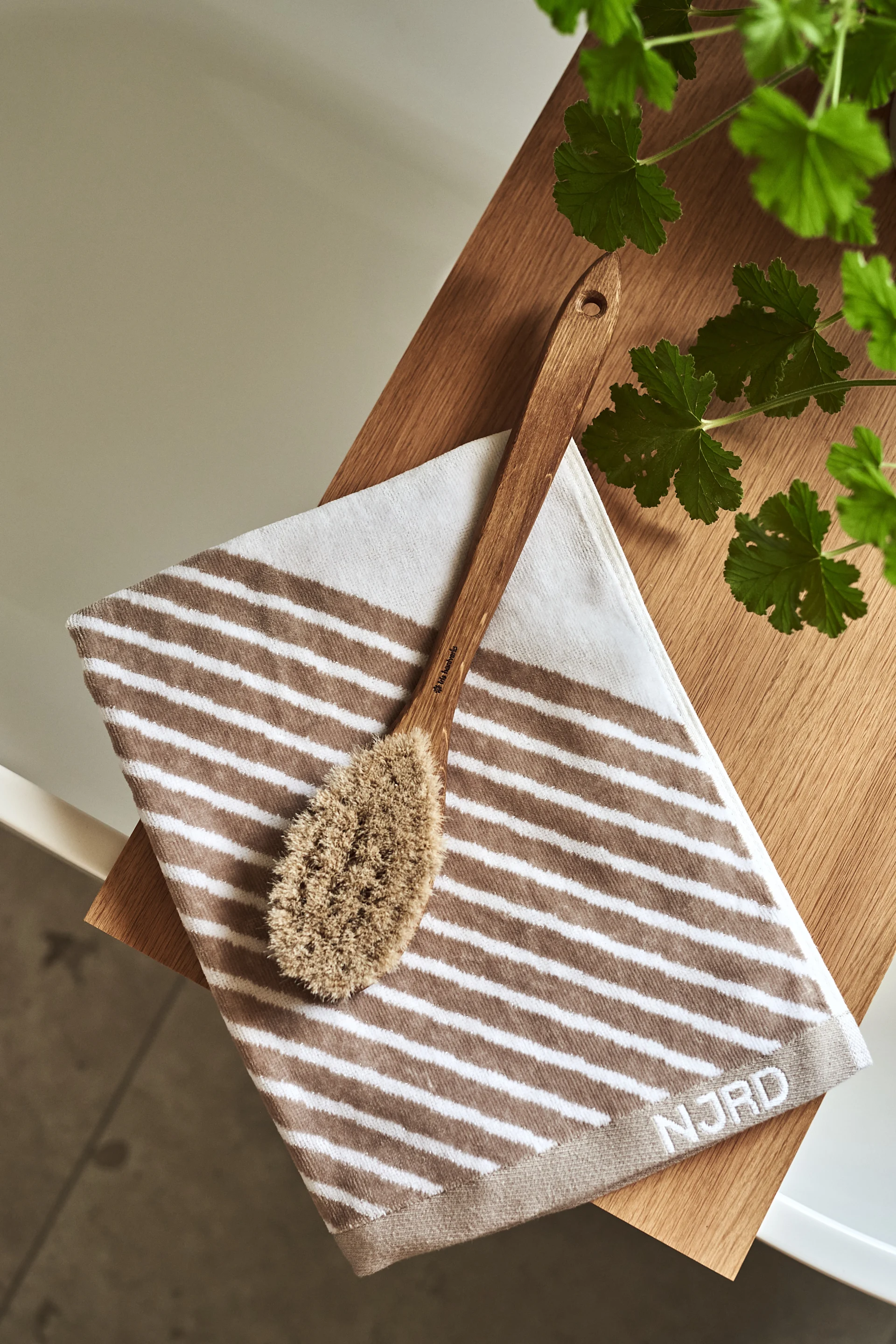 Crea la sensación de un spa en casa en tu cuarto de baño decorándolo con la toalla Stripes de NJRD y el cepillo de baño de Iris hantverk para disfrutar de momentos relajantes.