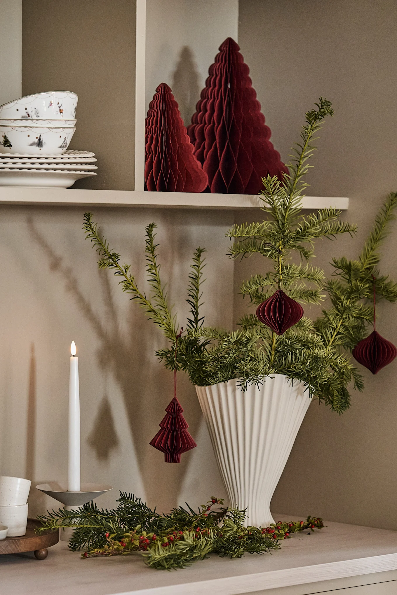 Decora un jarrón, como el jarrón Fountain de ferm LIVING, con ramas de abeto para crear un ambiente navideño en tu hogar, junto con adornos navideños de Scandi Living.