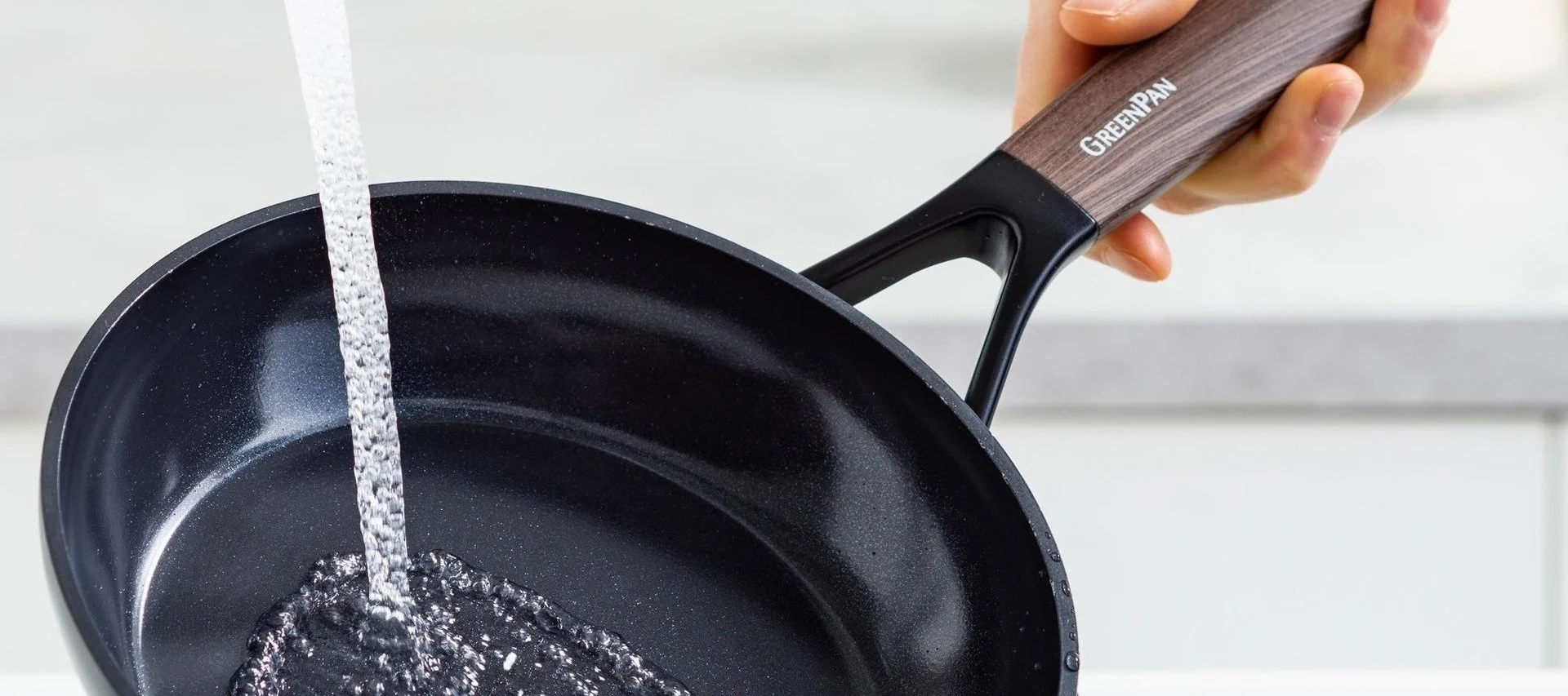 Limpia las sartenes, como la sartén Eco Smartshape de Greenpan, bajo el grifo.